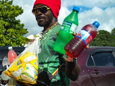 一名男子身穿绿色t恤，手里拿着两个贴有雪碧和蓝色标签的瓶子